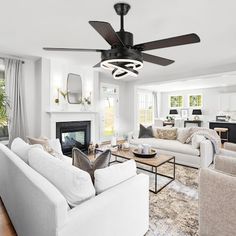 a living room filled with furniture and a fire place under a ceiling fan in front of a fireplace