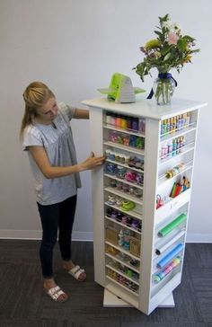 a woman standing next to a tall white shelf filled with items