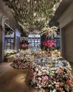 a room filled with lots of flowers and chandelier hanging from the ceiling above it