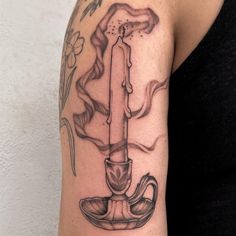 a woman's arm with a candle tattoo on it