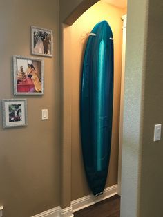 a blue surfboard is hanging on the wall next to some pictures and framed photos