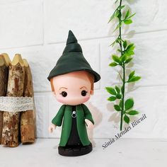 a small figurine sitting next to some logs and a plant on a table