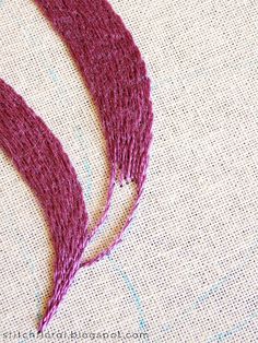 the stitches are being sewn together to make an embroidered necklace with red thread on it