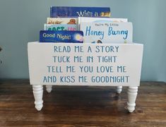 a small white bench with some books on it and a sign that reads read me a story tuck me in tight tell me you love me and kiss me goodnight