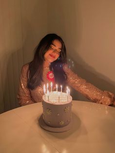 a woman sitting in front of a birthday cake with lit candles on top of it