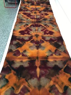 an orange and red rug on the floor next to a table with chairs in it