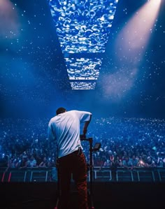 a man standing on top of a stage in front of a large group of people