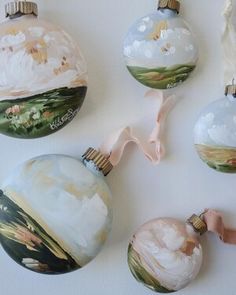 four glass ornaments are hanging on the wall, one is painted with flowers and clouds