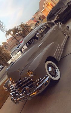 an old car is parked on the side of the road in front of a building