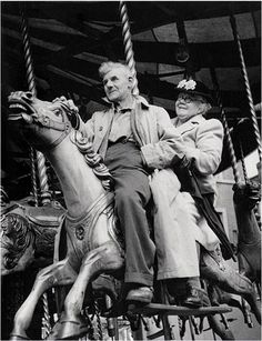 an old black and white photo of two people on a merry go round