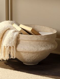 a white bowl filled with books on top of a wooden floor