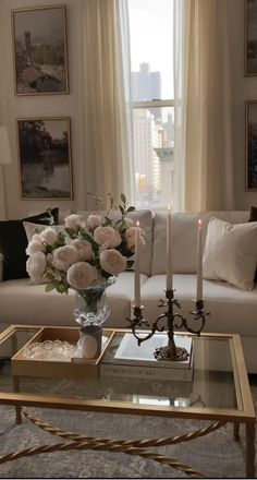 a living room filled with furniture and flowers on top of a coffee table in front of a window