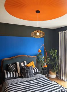 a bedroom with black and white striped bedding, orange ceiling fan and potted plants