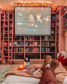 a person is sitting in front of a large screen with books and candles on it