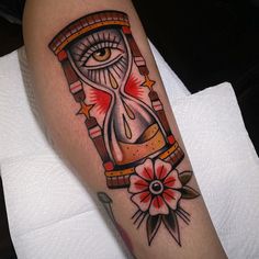 a tattoo on the leg of a person with an hourglass and flower in it