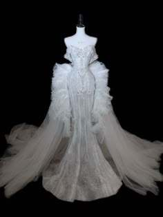 a white wedding dress on display in front of a black background