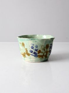 a blue and brown bowl sitting on top of a white table next to a wall