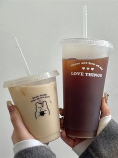 two people holding up cups with drinks in them, one is brown and the other is white