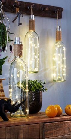 some bottles with lights in them are sitting on a table next to oranges and plants