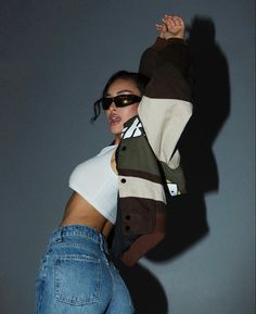 a woman in white shirt and jeans holding onto a skateboard with her arms up