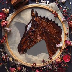 a brown horse head is shown on a wooden hoop with flowers and other items around it