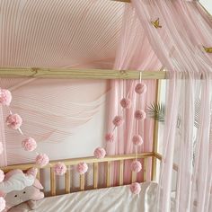 a baby's room decorated in pink and white with pom poms hanging from the ceiling