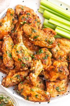 a white plate topped with chicken wings and celery sticks