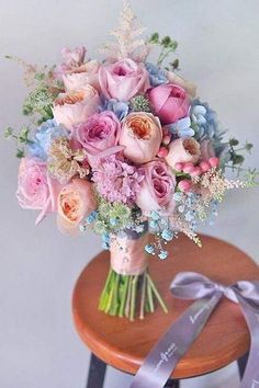 a bouquet of flowers sitting on top of a wooden table next to a purple ribbon