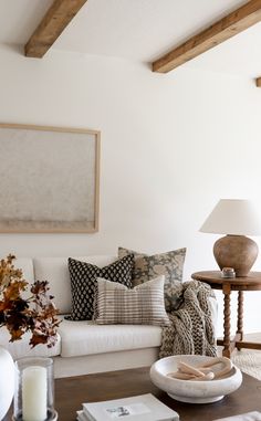 a living room with white couches and pillows on the coffee table in front of it