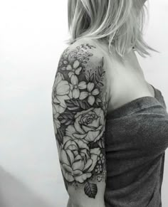 a black and white photo of a woman's arm with flowers tattooed on it