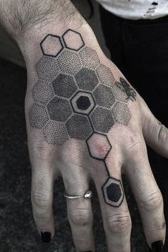 a person's hand with a black and white tattoo on it, hexagonal structure