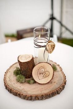 a candle and some wood slices on a white table cloth at a rustic wedding reception