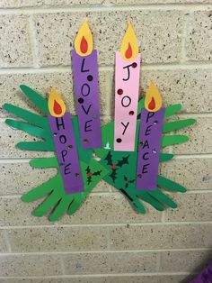 some paper candles with words on them hanging from a brick wall