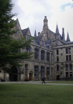 a person walking in front of a large building with towers on it's sides