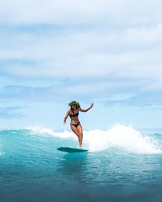 a woman riding a surfboard on top of a wave in the middle of the ocean