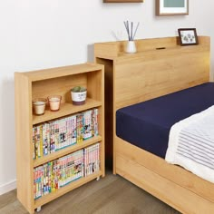 a bed with a book shelf next to it in a room that has white walls and wood floors