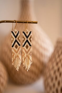 the beaded earrings are hanging from a wooden stick next to a vase with beads on it