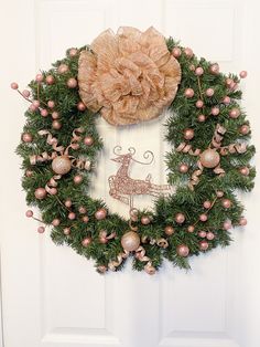 a christmas wreath hanging on the front door with ornaments around it and a decorative bow