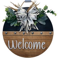 a welcome sign with flowers and leaves on the front, hanging from a wooden plaque