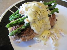 a white plate topped with meat covered in gravy and asparagus on top