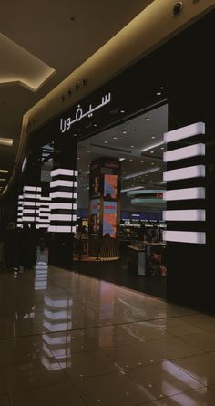 an empty shopping mall with people walking by the store front and signage on the wall