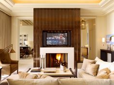 a living room filled with furniture and a flat screen tv mounted on the wall above a fire place