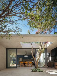 an open living room and dining area are separated by a concrete structure with glass doors