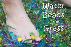 barefooted child's feet surrounded by beads and grass with text overlay reading water beads in the grass