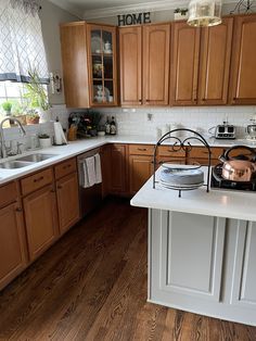 a kitchen with wooden cabinets and white counter tops, an island in the middle has a tea kettle on it