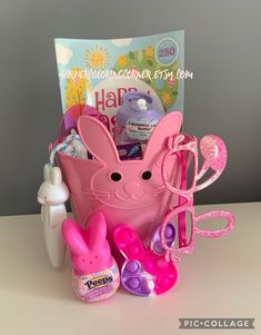 a pink basket filled with lots of toys on top of a white table next to a card