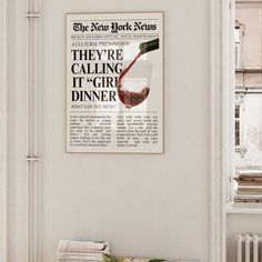 there is a newspaper with a wine glass on the wall next to some books and a plant