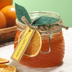 a jar filled with oranges sitting on top of a table next to sliced oranges