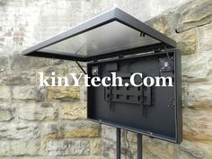 an outdoor tv stand with a glass top on the side of a stone wall next to a brick wall