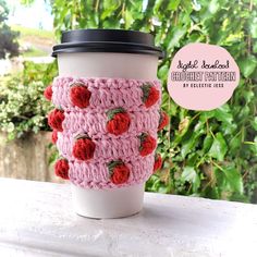 a crocheted coffee cup cozying with red roses on the outside and inside